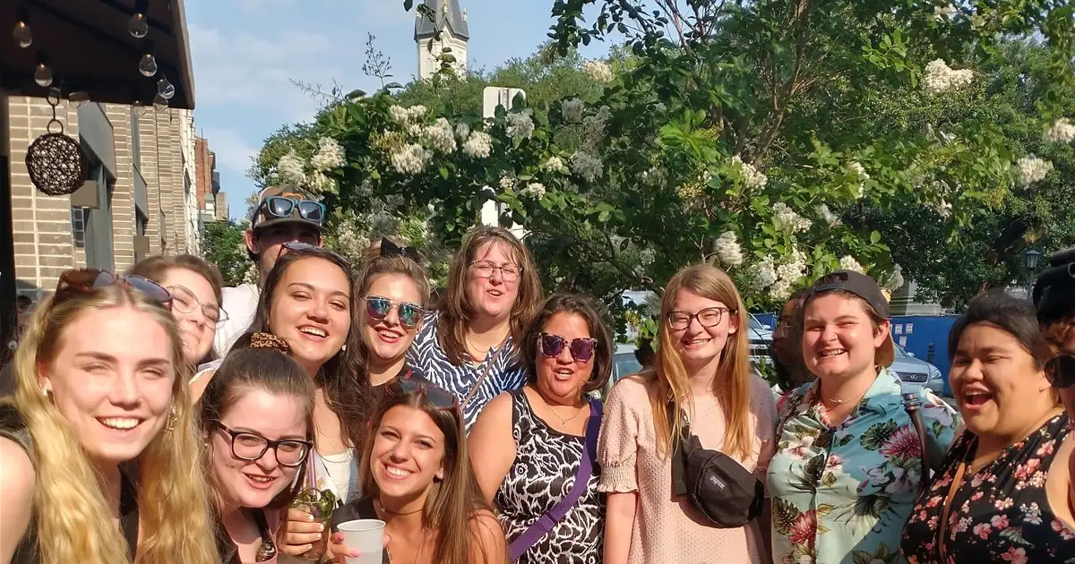 A group of friends with drinks on a Savannah street on a true crime pub crawl near ghost tours in Savannah GA